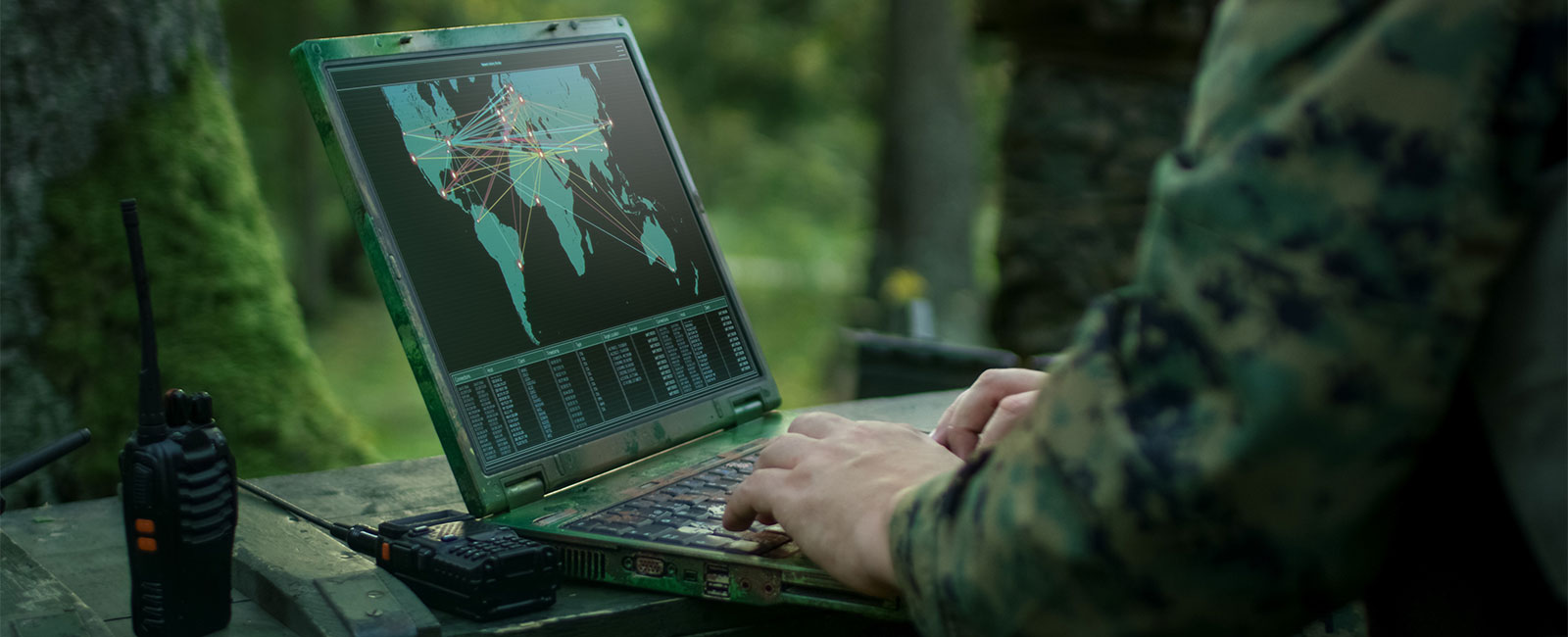 Soldiers using military laptop in forest